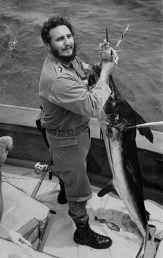 a man on a boat holding up a fish