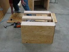 two men are working on some wooden furniture