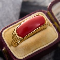 This pop of color ring features a rectangular orangey-red coral saddle. The shoulders of the ring are accented by vertical rope twists of gold. The ring is crafted in 14k yellow gold and is currently a size 7.25.  Jewelers epoxy helps secure the coral. Luxury Rectangular Ruby Ring, Heirloom Red Gold Signet Ring, Elegant Red 14k Gold Signet Ring, Rectangular Ruby Ring In Gold, Red Rectangular 14k Gold Jewelry, Rectangular Red 14k Gold Jewelry, Red Rectangular 14k Gold Ring, Formal Yellow Gold Jewelry With Red Coral, Art Deco Red Rectangular Jewelry