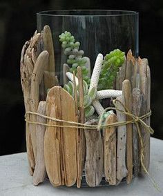 a glass vase filled with succulents and other plants sitting on top of a table