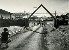 a group of people walking down a dirt road next to a wooden frame on the side of a hill