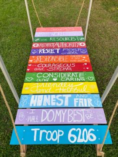 a colorful wooden sign sitting on top of a grass covered field