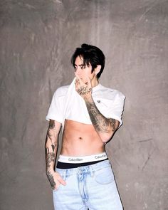 a man with tattoos standing in front of a wall