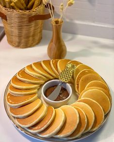 a plate with sliced oranges on it and a bowl of dipping sauce in the middle