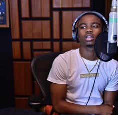 a young man sitting in front of a microphone wearing headphones and listening to music