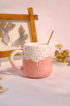 a pink cup with sprinkles and a straw in it sitting on a table