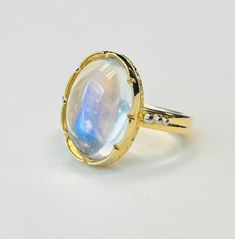 This pretty ring features a large oval moonstone weighing 8.70 carats with beautiful adularescence. Adularescence, or "billowy light effect" is the optical phenomenon that occurs in moonstone as light reflects off atomic layers inside the gemstone's crystalline structure. The glowing luster that results has the appearance of moonlight floating on water. Fine quality moonstones, especially those that exhibit a "blue flash" such as the one in this ring are rare. This moonstone is an impressive siz Modern Oval Cabochon Moonstone Ring, White Oval Cabochon Moonstone Ring, White Cabochon Moonstone Ring Fine Jewelry, White Cabochon Moonstone Ring In Fine Jewelry Style, Fine Jewelry White Cabochon Moonstone Ring, White Cabochon Moonstone Ring For Formal Occasions, Oval Moonstone Ring In White Gold, White Gold Cabochon Moonstone Ring, White Gold Moonstone Cabochon Ring