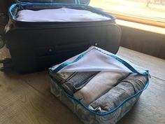 two pieces of luggage sitting on top of a wooden floor next to each other with clothes in them