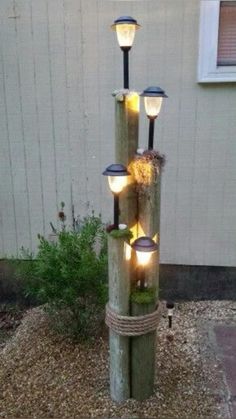 a light pole made out of logs with lights on it and moss growing in the middle