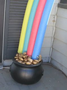 three surfboards sticking out of a black pot filled with rocks and pebbles in front of a garage door