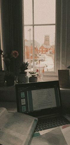 an open laptop computer sitting on top of a desk in front of a large window