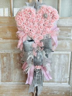 a bouquet of pink roses in the shape of a heart hanging on a door handle