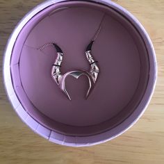 a purple bowl with two silver necklaces on it