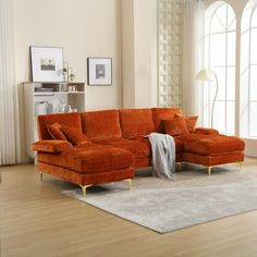 an orange sectional sofa sitting on top of a wooden floor next to a white rug