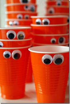 orange cups with eyes and googly eyes are lined up on a table in front of each other