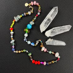 Dive into a kaleidoscope of color with our handcrafted Crystal Confetti Bead Necklace, a statement piece that promises to be as unique as you are. Each bead is lovingly hand-knotted, creating a flow of hues and textures that dance along a durable, colorful nylon cord. 🌟 Highlights:     Hand-knotted for durability and unique design     A vibrant mix of gemstones, glass, wood, ceramic, and resin beads     Bead sizes vary from 2-14mm for a dynamic visual texture     Approximately 21.5 inches in length, perfect for layering or as a standalone statement     Finished with lustrous gold plated stainless steel findings     Receive the exact necklace pictured in the photos 📏 Length: This enchanting necklace measures approximately 21.5 inches, a versatile length that complements both high and low Adjustable Multicolor Crystal Necklaces With Large Beads, Adjustable Multicolor Crystal Necklace With Large Beads, Spiritual Beaded Necklaces With Faceted Oval Beads, Spiritual Beaded Necklace With Faceted Oval Beads, Spiritual Colorful Beaded Necklace For Party, Colorful Faceted Beads Jewelry For Festivals, Multicolor Beaded Crystal Glass Necklaces, Rainbow Round Beads Necklace For Healing, Adjustable Rainbow Crystal Necklace With Faceted Beads