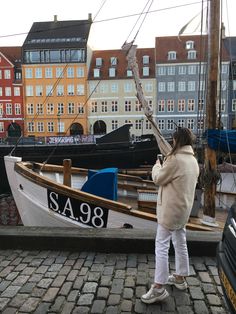 a woman standing next to a boat in the water