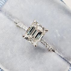 an emerald cut diamond engagement ring with pave diamonds