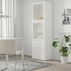 a white dining room table and chairs in front of a tall cabinet with glass doors