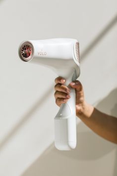 a woman is using a hair dryer to dry her hair on the wall while holding it in her hand