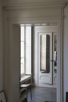 an empty room with a bench and mirror on the wall, in front of a window