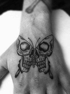 a hand with a skull and butterfly tattoo on it