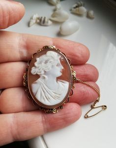 A Victorian / Edwardian carved shell cameo in a stamped 9ct gold frame and with safety chain attachment. It looks like it is a likeness for the reek Goddess Hera, who represents marriage, women and family. She is said to protect women during childbirth, especially. This cameo brooch pleasingly, has the old English Edwardian plaque of "9ct" on it and also has some etched lettering, numbers by the craftsperson or perhaps a dedication to someone? It reads "Gb 16" which I believe refers to the someo Art Nouveau Oval Cameo Jewelry, Art Nouveau Yellow Gold Intaglio Jewelry, Gold Art Nouveau Jewelry With Intaglio, Classic Gold Cameo Jewelry, Antique Cameo Yellow Gold Jewelry, Antique Yellow Gold Cameo Jewelry, Gold Cameo Jewelry In Art Nouveau Style, Art Nouveau Cameo Jewelry Gift, Heirloom Gold Cameo Jewelry