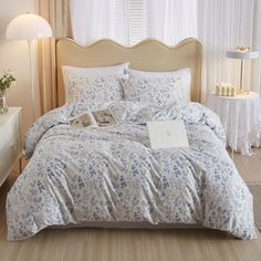 a bed with blue and white flowers on it in a bedroom next to a window