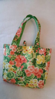 a flowered bag is sitting on a white surface with a green strap around it