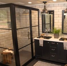 a bathroom with two sinks, mirrors and lights on the wall next to a walk in shower