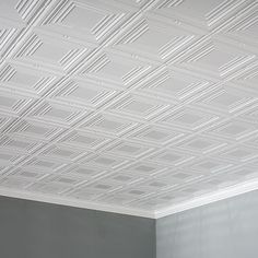 an empty room with white painted ceiling tiles