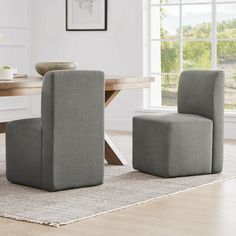 two grey chairs sitting in front of a wooden table