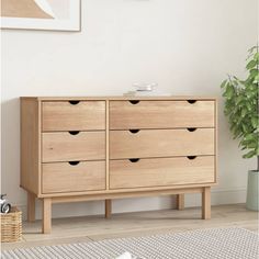 a large wooden dresser with drawers in a living room next to a potted plant