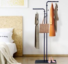 there is a coat rack with shoes and purses on it in front of a bed