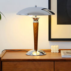 a table lamp sitting on top of a wooden desk next to a framed photograph and a book