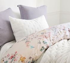 the comforter is made up with white sheets and purple pillow cases on top of it