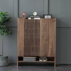 a wooden cabinet sitting next to a potted plant