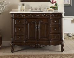 a bathroom vanity with a mirror above it and flowers on the counter top in front of it