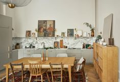 a dining room table and chairs in front of a kitchen counter with pictures on the wall