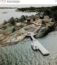 an aerial view of a boat dock on the water near a house and some rocks