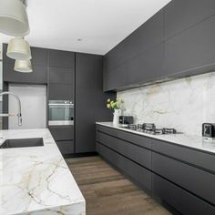 a modern kitchen with marble counter tops and dark gray cabinets, along with an island