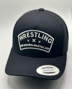 a black wrestling hat with white lettering on the front and back side, sitting on a table