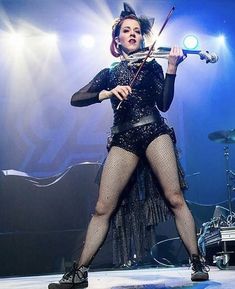 a woman in fishnet stockings holding a violin on stage