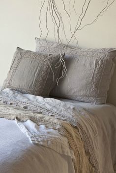 a bed with two pillows and some branches on the headboard