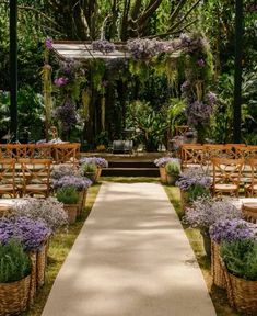 an outdoor ceremony with wooden benches and wicker baskets filled with purple flowers on the aisle