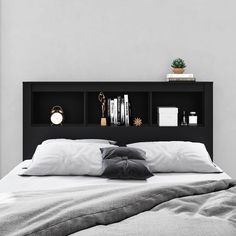 a bed with white sheets and pillows in front of a black bookcase that has books on it