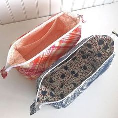 two purses sitting on top of a white table