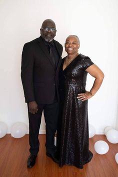 a man and woman standing next to each other in front of white balloons on the floor