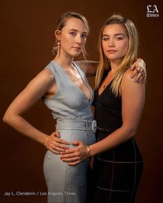 two beautiful young women standing next to each other in front of a brown background with their arms around each other