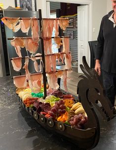 a man standing in front of a boat filled with meats and other food items